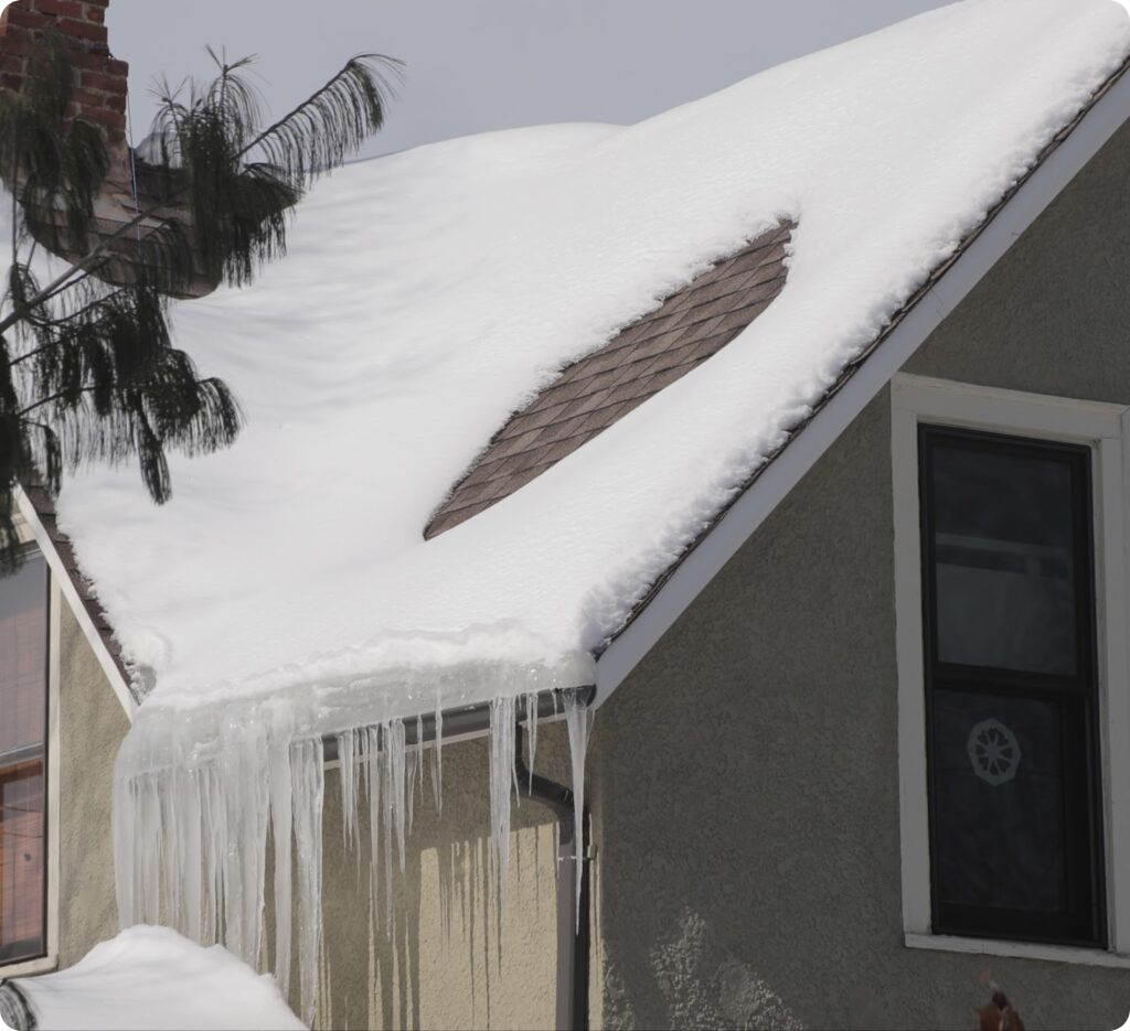 Severe ice buildup blocking a gutter downspout on a brick building. This image shows how frozen gutters form without self-regulating heat tape, highlighting the importance of using UL-listed heat cables to prevent ice dams and winter roof damage.